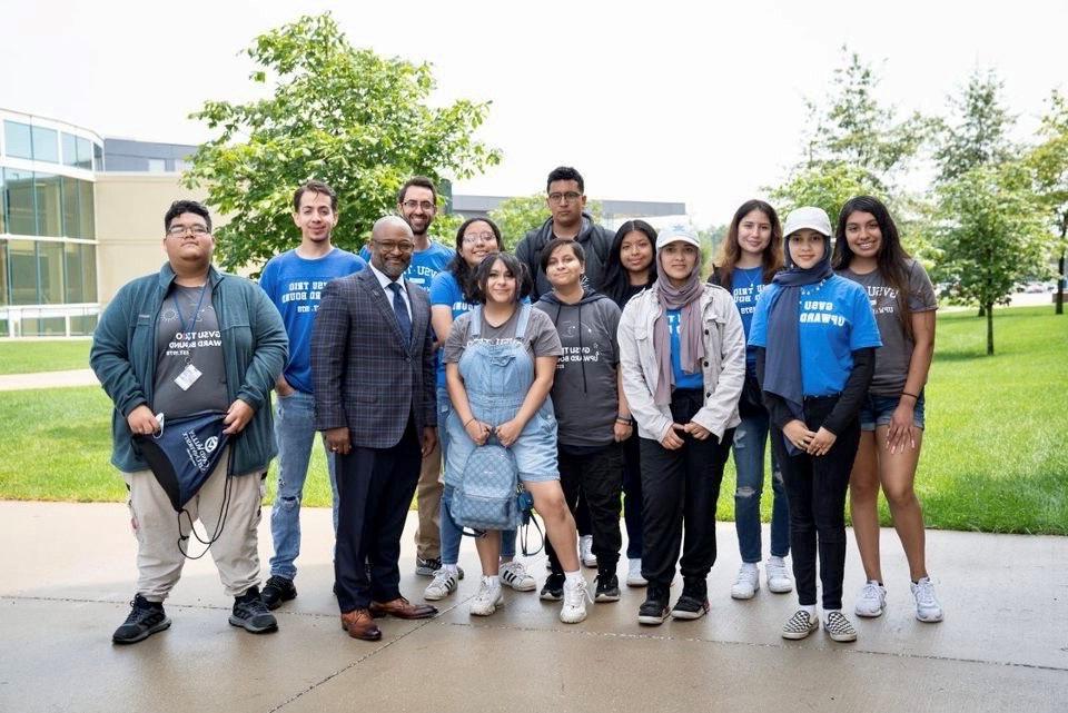 group photo of students and GVSU leaders standing in front of a building on campus